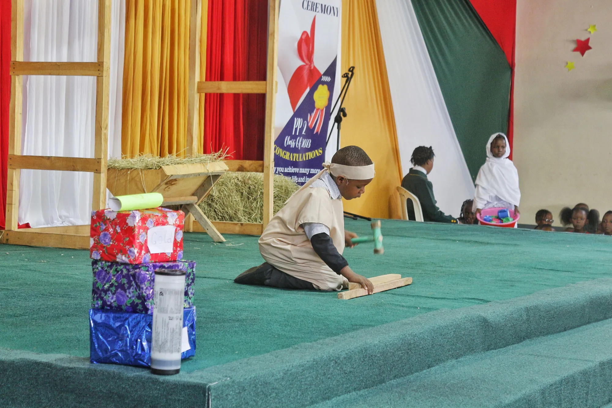 Children performing a nativity play on a stage with curtains