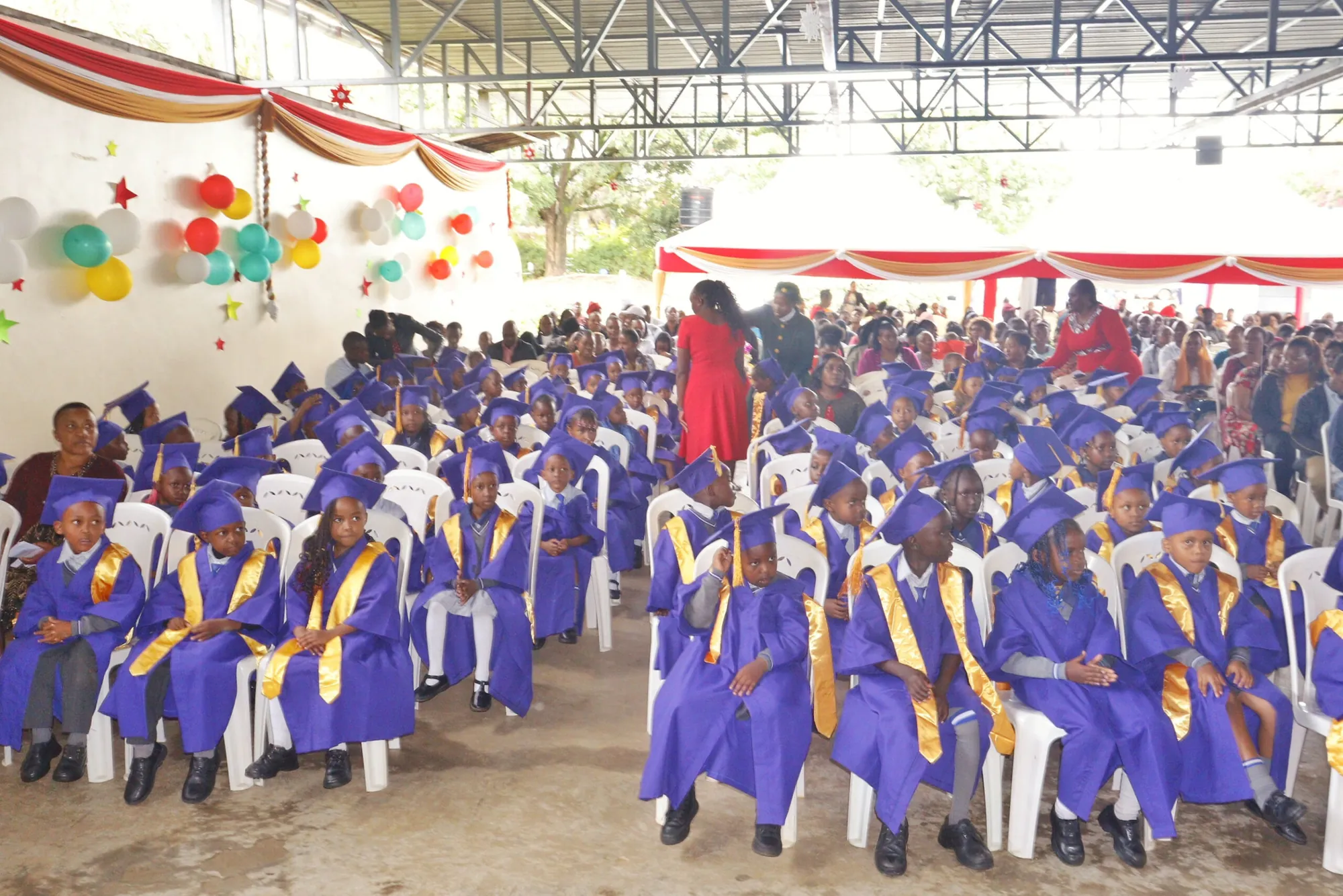 Rows of graduating pupils in purple caps and gowns at a school ceremony
