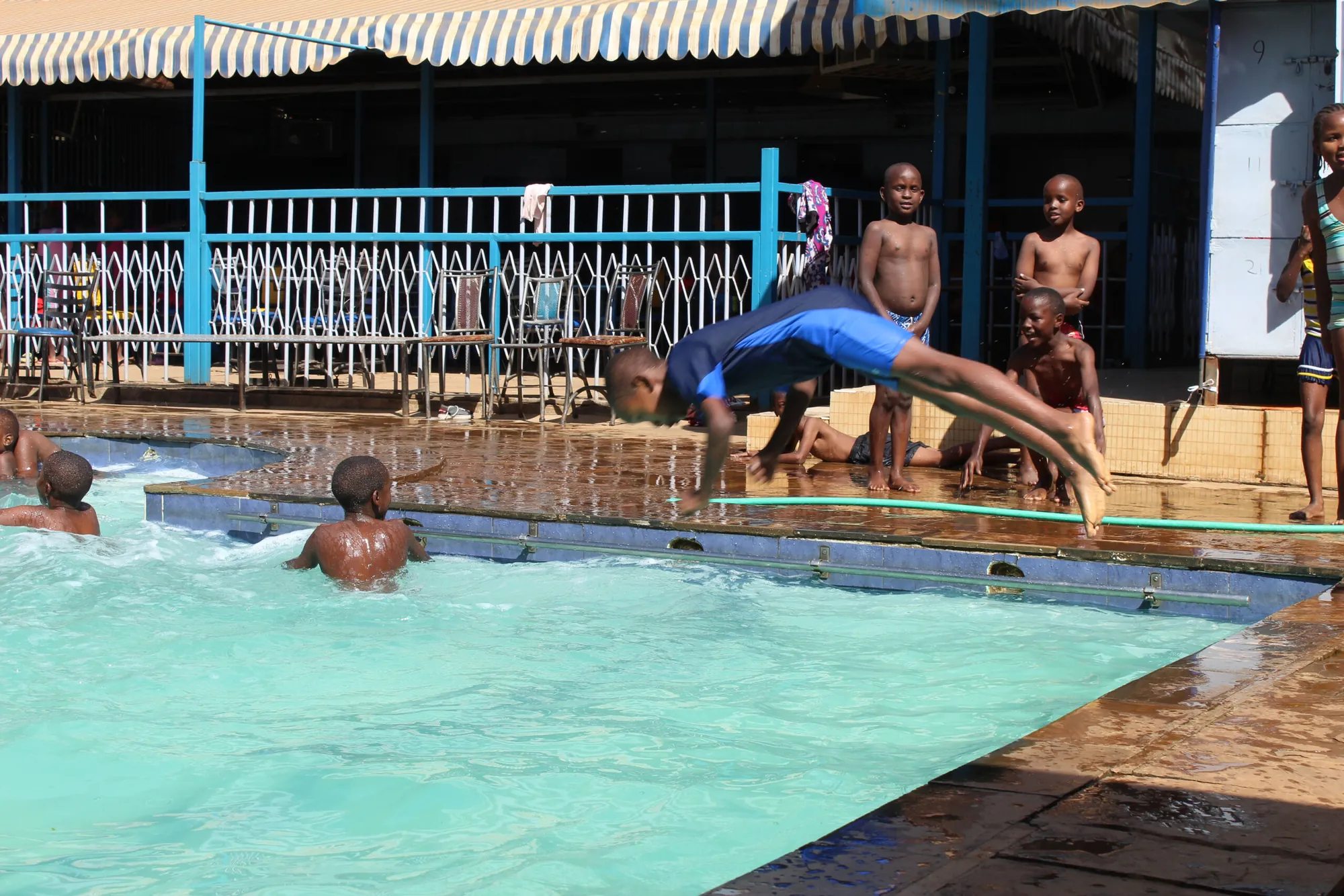 A pupil diving into the school swimming pool while others watch
