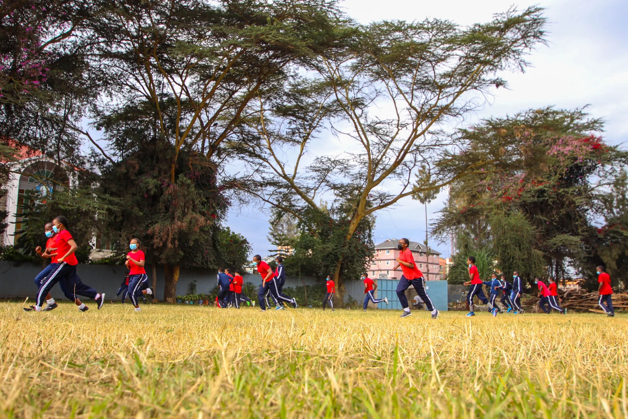 Pupils in red sports kit playing on the school field